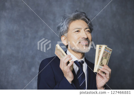 Smiling senior businessman holding a stack of bills 127466881
