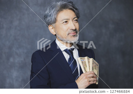 微笑的高級商人拿著一疊鈔票 微笑的高級商人拿著一疊鈔票 127466884