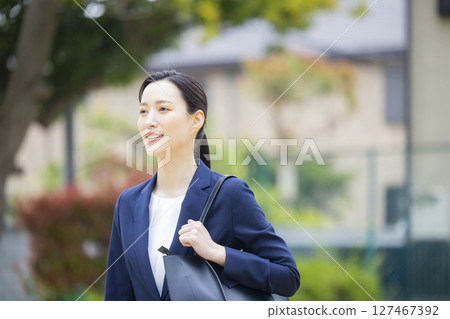 A young woman in a suit walking through a residential area 127467392
