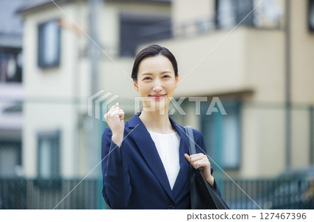 一位身著西裝的年輕女子走過居民區 127467396