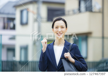 一位身著西裝的年輕女子走過居民區 127467397