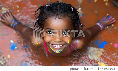 Joyful Child Covered in Paint, Smiling Upward with Open Arms Joyful Child Covered in Paint, Smiling Upward with Open Arms 127468594