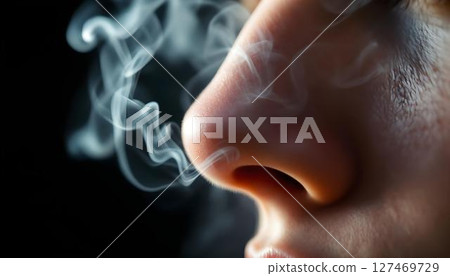 Close-up of a woman's nose with wisps of smoke gently rising from it, creating a dramatic and intriguing visual effect 127469729