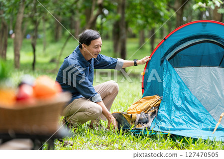 Family adventure. A father setting up a tent while enjoying nature. 127470505