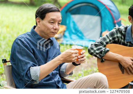 Family moments captured. Father enjoying coffee while son plays guitar. 127470508