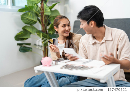 Financial Empowerment. Young couple discussing budgeting while reviewing credit card and smartphone. Financial Empowerment. Young couple discussing budgeting while reviewing credit card and smartphone. 127470521