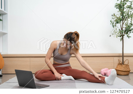 Yoga practice at home. Young woman performing forward bends for flexibility and relaxation. Yoga practice at home. Young woman performing forward bends for flexibility and relaxation. 127470527