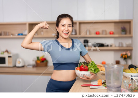 ESG and Empowerment. Confident woman flexing her muscles while holding fresh produce. 127470629