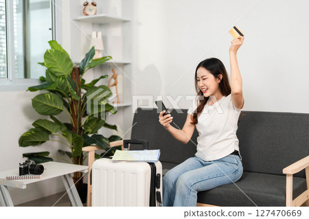 Travel excitement. Young woman celebrating successful online booking with smartphone. 127470669