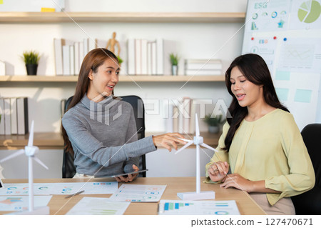 ESG Strategy Session. Two women brainstorming sustainable solutions in an eco-friendly workspace. ESG Strategy Session. Two women brainstorming sustainable solutions in an eco-friendly workspace. 127470671