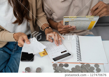 Couple Budgeting Together. Young partners managing finances with calculator and notes. Couple Budgeting Together. Young partners managing finances with calculator and notes. 127470676