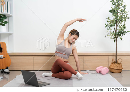 Yoga practice at home. Young woman performing side stretches for flexibility and mindfulness. Yoga practice at home. Young woman performing side stretches for flexibility and mindfulness. 127470680