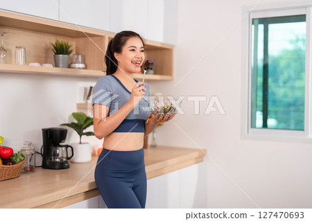 ESG and Enjoying Healthy Food. Woman savoring a fresh salad in her kitchen. 127470693