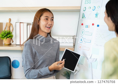 ESG Presentation. Young professional explaining sustainability metrics to colleagues. ESG Presentation. Young professional explaining sustainability metrics to colleagues. 127470708