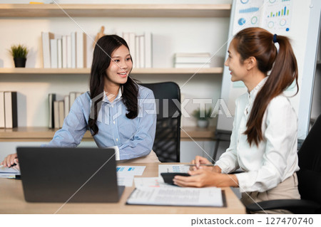 Business Strategy Meeting. Two women collaborating on project analysis in an office environment. 127470740