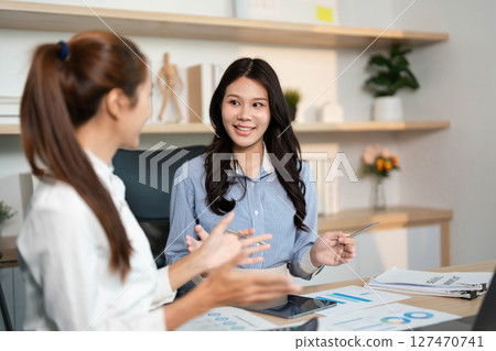 Dynamic Team Collaboration. Two women engaging in financial discussions at their workplace. 127470741