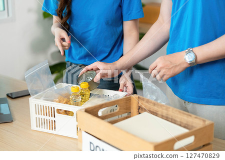 Donation and Community Support. Volunteers organizing food donations in a community center. Donation and Community Support. Volunteers organizing food donations in a community center. 127470829