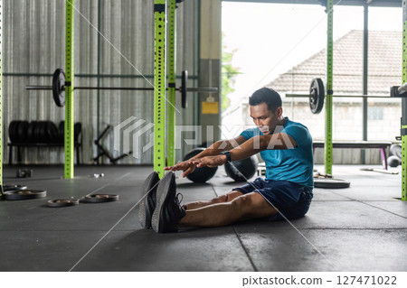 Fitness Stretch. Man reaching forward in a gym for flexibility. Fitness Stretch. Man reaching forward in a gym for flexibility. 127471022