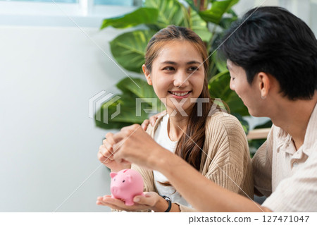 Couple Collaborating on Financial Goals. Engaging in budgeting with a piggy bank and calculator. Couple Collaborating on Financial Goals. Engaging in budgeting with a piggy bank and calculator. 127471047