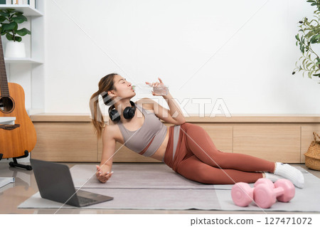Yoga and Wellness. Woman practicing yoga and hydrating at home. 127471072