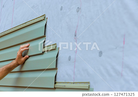 Work progresses on modern building exterior with green vinyl paneling installation Work progresses on modern building exterior with green vinyl paneling installation 127471325