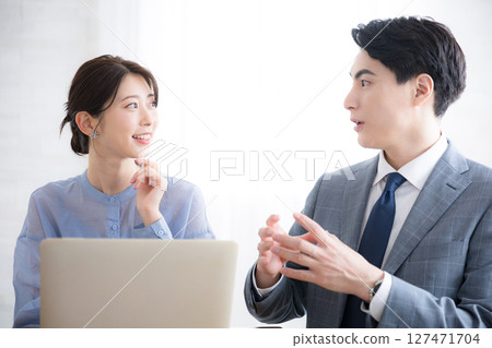 Businessmen and women in suits looking at computers in an office Businessmen and women in suits looking at computers in an office 127471704