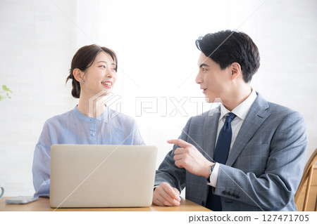 Businessmen and women in suits looking at computers in an office Businessmen and women in suits looking at computers in an office 127471705