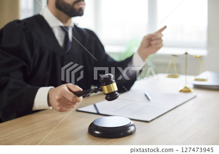 Man judge knocking gavel having court verdict sitting at the desk on workplace in courtroom 127473945