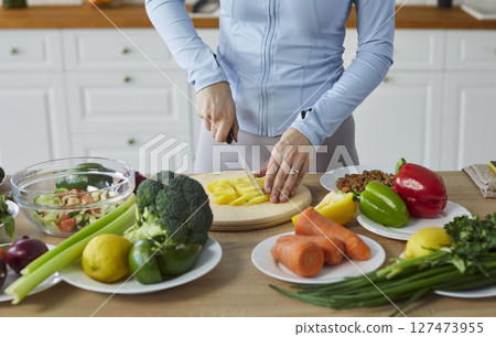 Woman cutting salad healthy vegans cooking at home in modern kitchen, vegetarian diet assortiment Woman cutting salad healthy vegans cooking at home in modern kitchen, vegetarian diet assortiment 127473955
