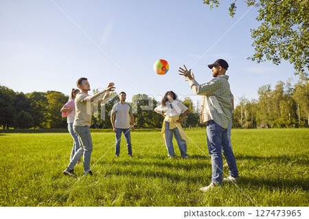 Happy joyful young people friends in casual clothes playing with ball in the summer park. 127473965