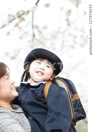 Cherry blossoms and a 3-year-old girl and her mother at the kindergarten entrance ceremony 127474255