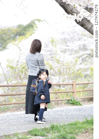Cherry blossoms and a 3-year-old girl and her mother at the kindergarten entrance ceremony 127474279