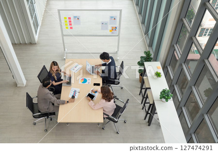 High-powered business professional discussing strategic plan and making decision at a conference table in a professional office setting. 127474291