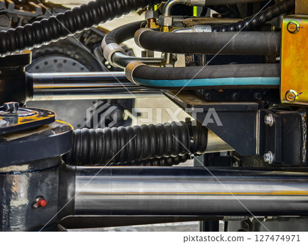 Close-up view of hydraulic system components in heavy machinery at a construction site during daytime Close-up view of hydraulic system components in heavy machinery at a construction site during daytime 127474971