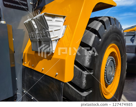 Heavy machinery tire and fender details capture in bright sunlight at construction site during daytime activity Heavy machinery tire and fender details capture in bright sunlight at construction site during daytime activity 127474985