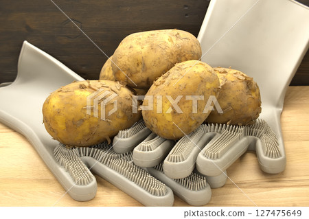 Fresh potatoes are resting on a special cleaning glove, ready for cooking. Fresh potatoes are resting on a special cleaning glove, ready for cooking. 127475649