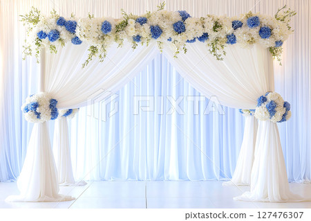 Beautiful wedding arch decorated with blue and white flowers and sheer curtains creates a romantic atmosphere 127476307
