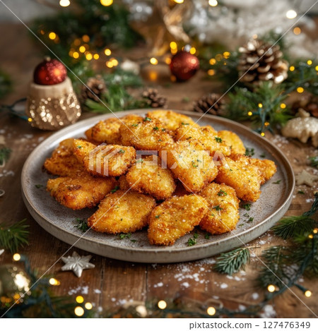 Golden crispy fried fish pieces perfect for a celebration or cozy dinner. Appetizingly served against a backdrop of Christmas decorations, creating an atmosphere of warmth and festivity.  127476349