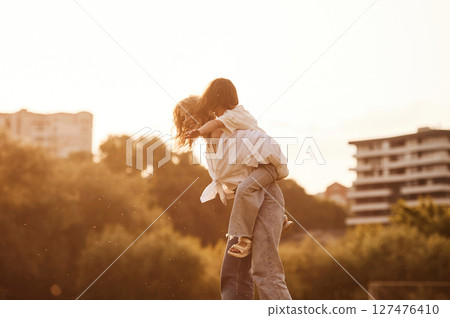 Sitting on the mother shoulders. Woman with her little daughter are on the summer field together 127476410