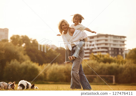 Beautiful mother with her little daughter and dogs are on the summer field together Beautiful mother with her little daughter and dogs are on the summer field together 127476411