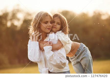 Conception of love, embracing each other. Woman with her little daughter are on the summer field together Conception of love, embracing each other. Woman with her little daughter are on the summer field together 127476420