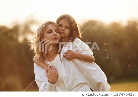 Conception of love, embracing each other. Woman with her little daughter are on the summer field together Conception of love, embracing each other. Woman with her little daughter are on the summer field together 127476422