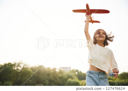 Happy little girl is playing with toy plane outdoors 127476624