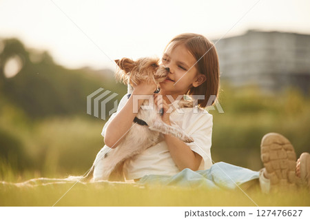 Little girl is playing with dog on the summer field 127476627
