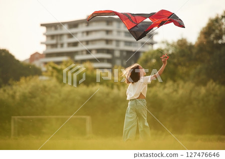 View from behind. Little girl is playing with kite on the field View from behind. Little girl is playing with kite on the field 127476646