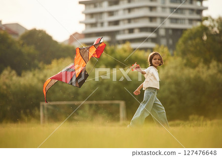 Little girl is playing with kite on the field Little girl is playing with kite on the field 127476648