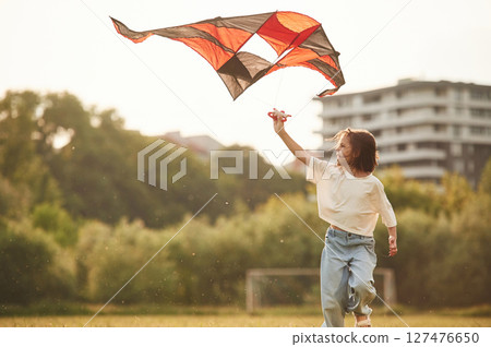 Little girl is playing with kite on the field Little girl is playing with kite on the field 127476650
