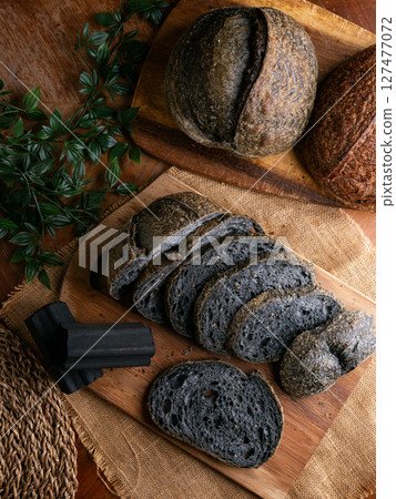 Fresh baked black charcoal sourdough ciabatta bread sliced on wooden board. Fresh baked black charcoal sourdough ciabatta bread sliced on wooden board. 127477072