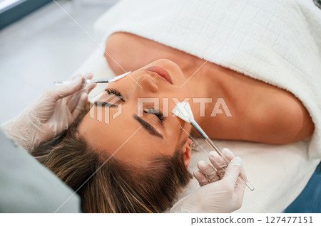 Brushes are used to clean skin. Woman face getting facial care by beautician hands at spa salon Brushes are used to clean skin. Woman face getting facial care by beautician hands at spa salon 127477151