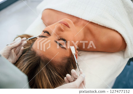 Brushes are used to clean skin. Woman face getting facial care by beautician hands at spa salon 127477152